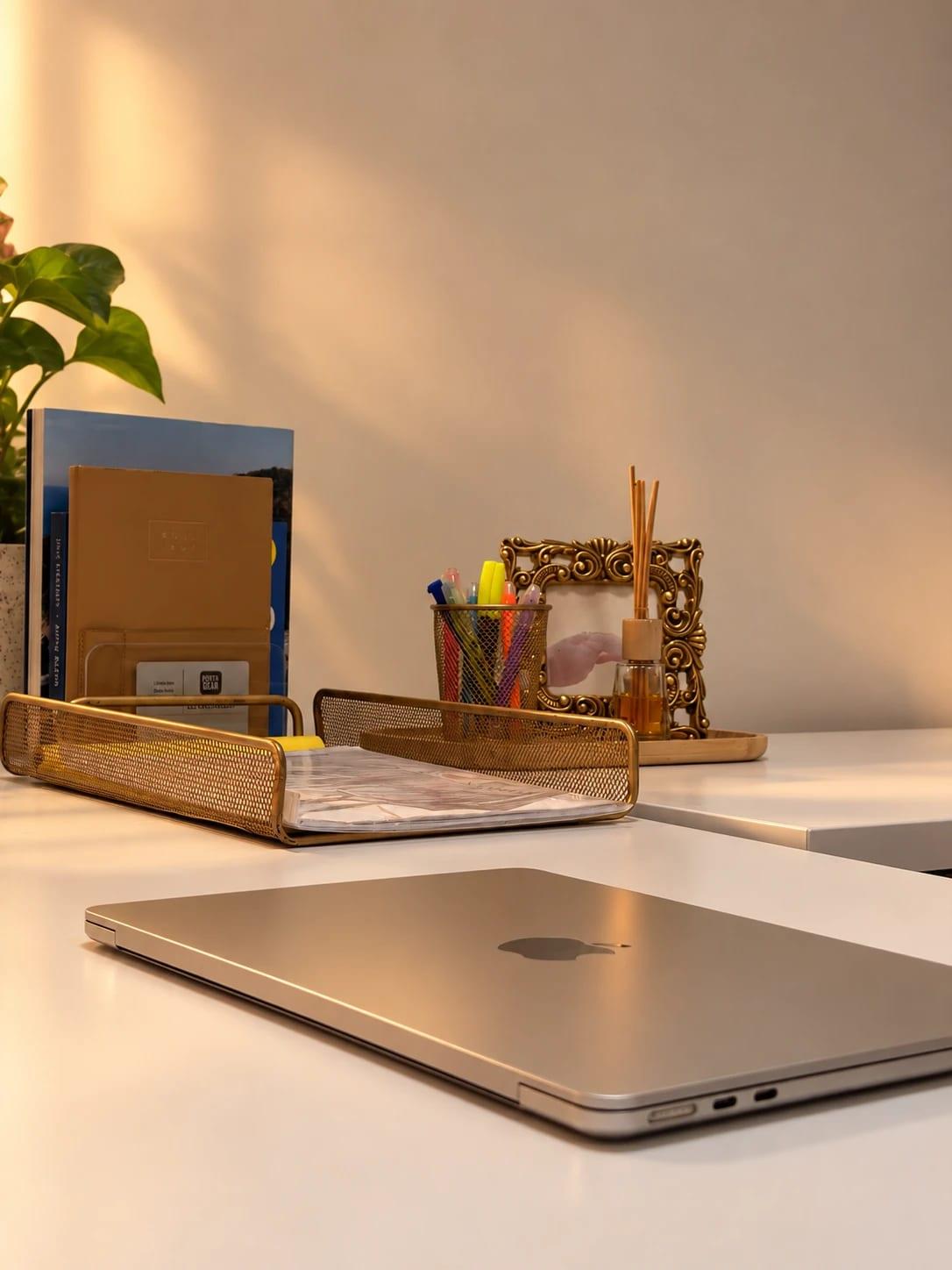 Desk with a laptop, golden tray and plant in warm light