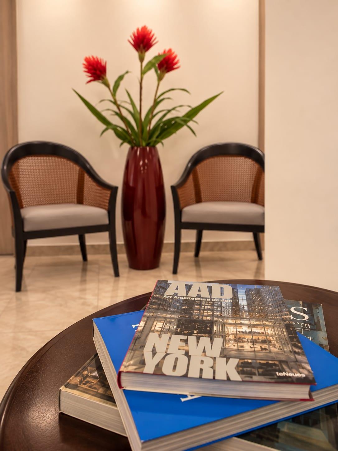 Rattan armchairs beside red flowers and architecture books